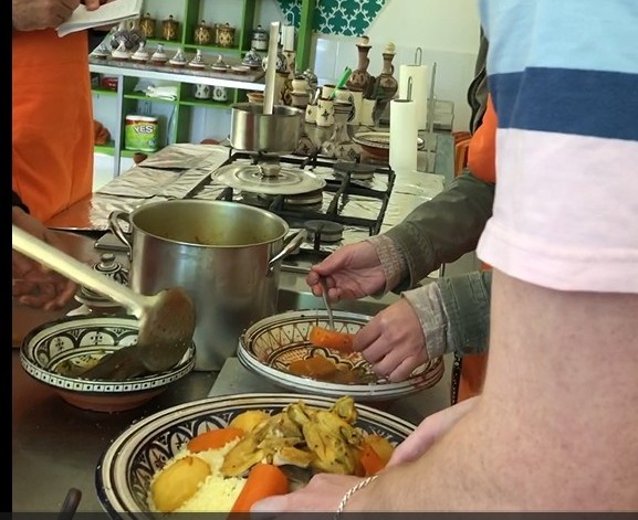 Hands preparing a dish with vegetables and sauce in a kitchen setting.