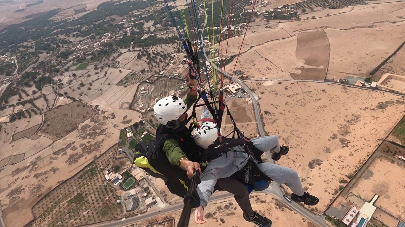 Two paragliders soaring above a vast desert landscape.