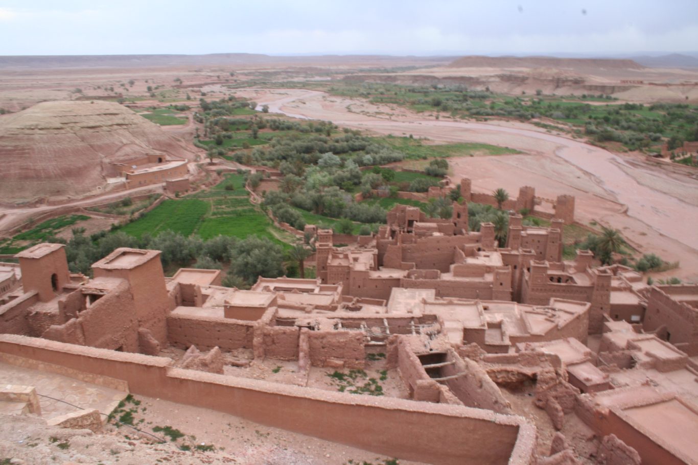 Ait Ben Haddou valley Panoramic view of a desert landscape with ancient ruins and lush greenery near a river.
